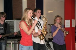 Drie jonge muzikanten met sax, trompet en microfoon